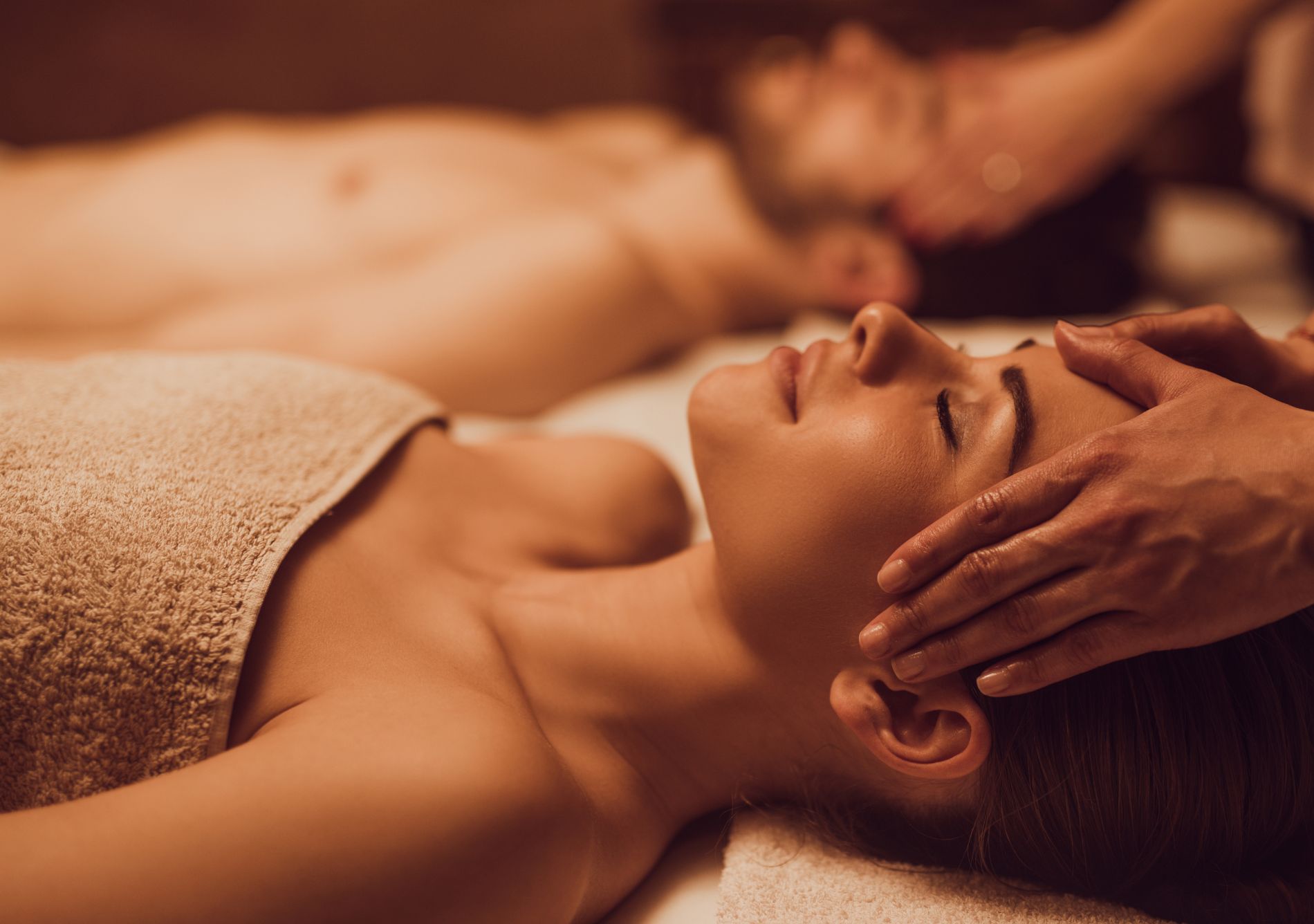 A couple is getting massages in a darkened room while lying on their backs