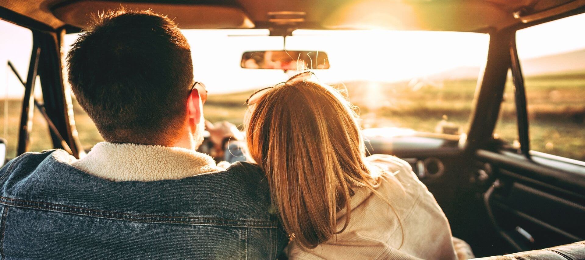 A couple driving together through the countryside at sunset during a fall getaway.
