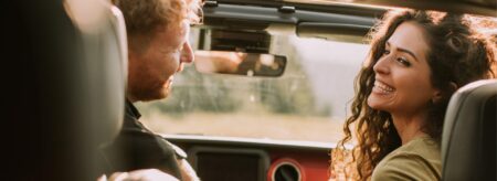 couple smiling together inside a vehicle during a road trip