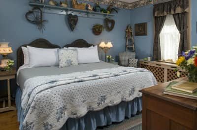 Blue room with heart shaped wicker wreaths hanging over a bed with a blue and white comforter